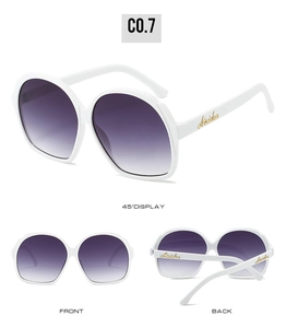 Detail of white oval sunglasses with purple gradient lenses and gold logo