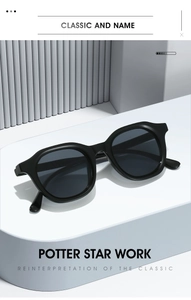 Detail view of vintage oval sunglasses with thick black frames on a modern display stand