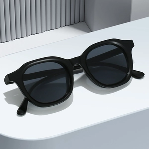 Classic black oval sunglasses with thick frames on a minimalist gray geometric background