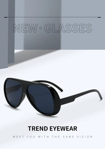 Detail of oversized black pilot sunglasses with dark blue lenses and modern resin frame