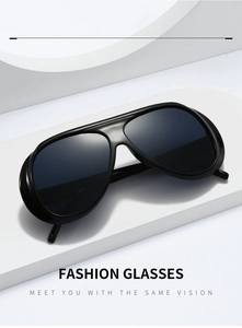 Detail of glossy black aviator sunglasses with large frames on a white platform