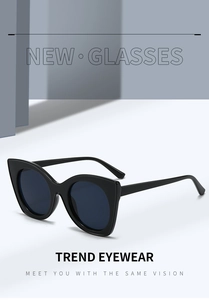 Close-up of black oversized cat-eye sunglasses with dark blue lenses and sleek glossy frames