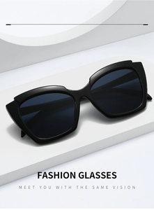 Close-up of black oversized cat-eye sunglasses on a white geometric stage background