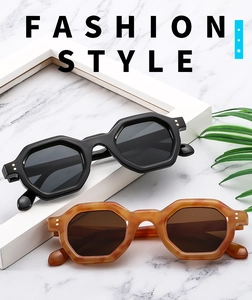 Detail view of geometric sunglasses with dual-dot rivets on black and amber frames
