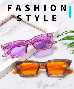 Modische Cat-Eye-Sonnenbrille in Lila und Orange auf weißem Marmorhintergrund