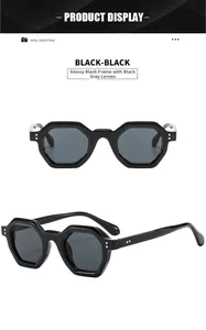 Close-up of hexagonal sunglasses with glossy black frames and gold rivet details