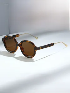 Close-up of tortoise shell oval sunglasses with slim gold metal temples and brown lenses