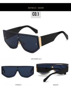 Detail view of oversized frameless shield sunglasses with golden metal hinges and dark lens