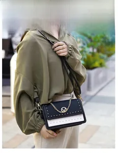 Détail d'un sac à bandoulière bicolore chic avec clous dorés et logo V sur le mannequin