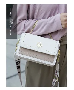 Détail du sac bandoulière avec rivets, chaîne dorée et bandoulière tissée décorative