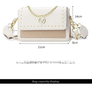 Détail du sac carré bicolore avec clous dorés et fermoir en V en métal sur cuir blanc