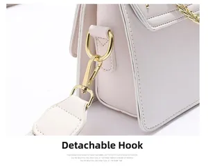 Détail du crochet doré amovible sur un sac à bandoulière en cuir rose pour femme