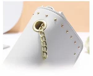Gros plan sur la texture du cuir blanc avec clous dorés et détails de chaîne en métal
