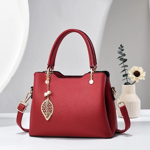Elegante rote Lederhandtasche mit goldenem Blattanhänger und verstellbarem Riemen