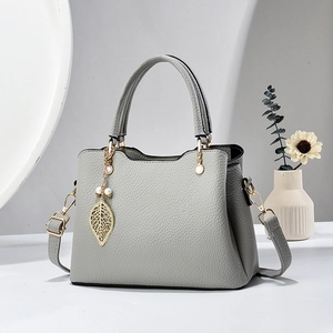 Elegante graue Handtasche mit Litschi-Textur, goldenem Blattanhänger und Riemen