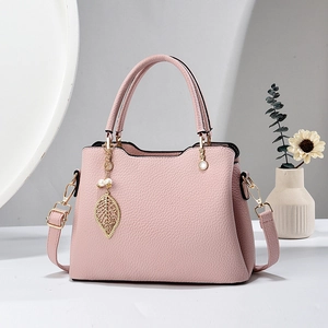 Rosa Handtasche mit Litschi-Lederoptik, goldenem Blattanhänger und Perlenakzenten