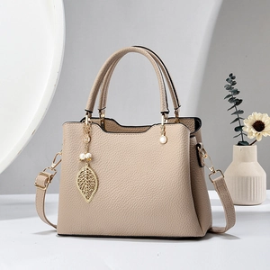 Elegante apricotfarbene Handtasche aus Leder mit Blattanhänger und Schultergurt