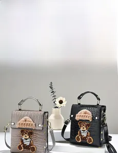 Detail of gray and black crocodile texture crossbody bags with cute teddy bear patch