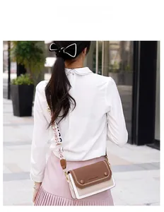 Détail du sac bandoulière bicolore avec large sangle à motifs porté par un mannequin