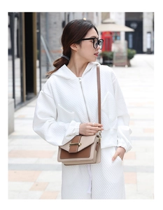 Vue détaillée du sac bandoulière beige et marron avec boucle en métal sur modèle en survêtement
