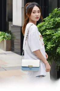Détail d'un sac bandoulière blanc et bleu avec fermoir fleur dorée et sangle tissée