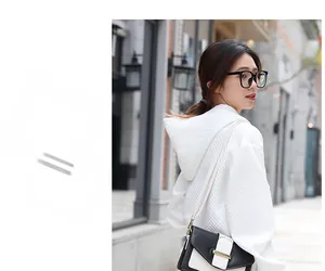 Détail d'un sweat à capuche gaufré blanc avec un sac à bandoulière contrasté noir et blanc