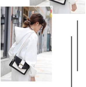 Détail d'un sac bandoulière chic bicolore noir et blanc avec une boucle en métal sur le rabat