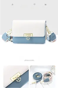 Détail du sac bandoulière bleu et blanc avec fermoir fleur dorée et deux bandoulières