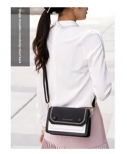 Détail d'un sac bandoulière en cuir noir et blanc avec sangle réglable et bordure dorée