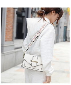 Gros plan du sac carré blanc minimaliste doté d'une large bandoulière brodée colorée