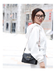 Détail d'un sac bandoulière noir avec une large sangle tissée au style ethnique