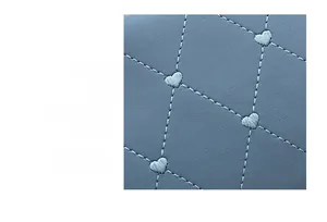 Detail of blue quilted leather bag featuring white heart embroidery and diamond stitching
