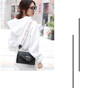 Détail de la sacoche en cuir noir avec une large bandoulière brodée de style ethnique