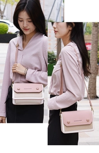Détail du sac à bandoulière macaron bicolore avec chaîne dorée porté par un mannequin