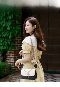 Detail of elegant two-tone square bag with heart stitching and floral woven strap