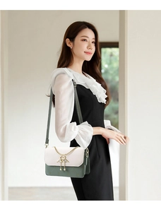 Detail of green quilted crossbody bag with golden swan closure and chain handle