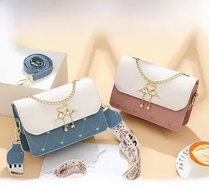 Detailed shot of small square bags with swan buckles and pearl charms in pink and blue