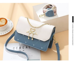 Detail of color-block square bag with heart stitching and pearl swan buckle on desk