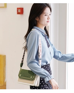 Détail d'un sac bandoulière color-block avec larges sangles brodées et lettrées