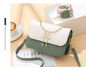 Detail of crossbody bag with embroidered wide strap and pearl swan heart clasp