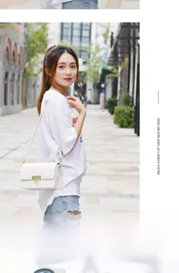 Sac bandoulière blanc rectangulaire avec fermoir fleur dorée porté par un mannequin
