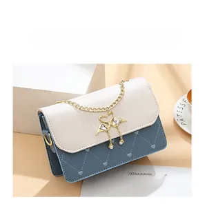 Detail of a color-block square bag featuring swan buckles and heart stitched patterns