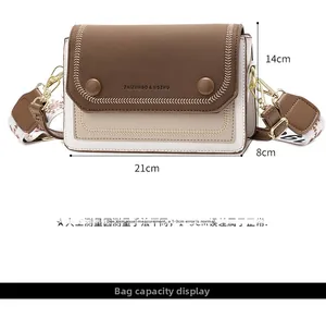 Détail du sac bandoulière bicolore avec surpiqûres et large sangle à motifs