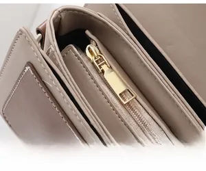 Détail macro de la fermeture éclair dorée sur le sac en cuir couleur taupe