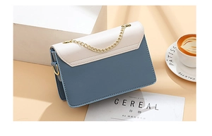 Detail of color-block square bag with blue leather, white flap and golden chain strap