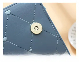 Detail of light blue leather bag with heart quilting and golden magnetic snap closure