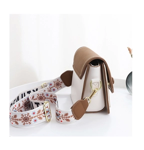 Détail du sac bandoulière bicolore avec sangle brodée et lettrage BEAUTY élégant