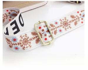 Gros plan sur une bandoulière ethnique brodée avec fleurs et boucles métalliques dorées