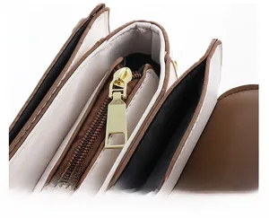 Détail d'un sac à trois compartiments avec fermetures éclair dorées et coutures contrastées