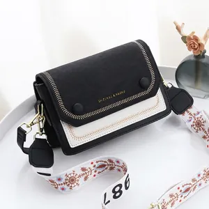 Sac bandoulière noir et blanc chic avec bandoulière brodée sur un plateau blanc